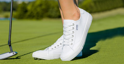close up of womens White swingdish traveler spikeless shoe while standing on a golf course 